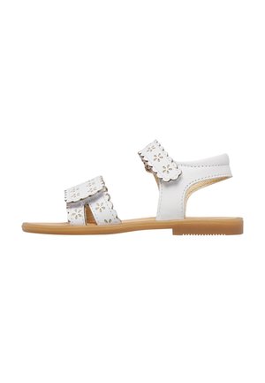 Sandale blanche pour enfants avec deux brides réglables présentant des motifs de découpe en forme de fleurs et une semelle plate de couleur beige.