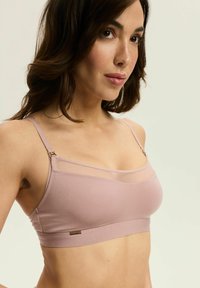Jasnoróżowy miękki stanik braletka z cienkimi regulowanymi ramiączkami, przezroczystą górną częścią oraz złotymi akcentami na boku.