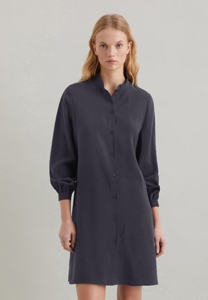 Dunkelblaues Hemdblusenkleid mit Stehkragen, langen Puffärmeln und geradem Schnitt, aus glattem Stoff gefertigt.