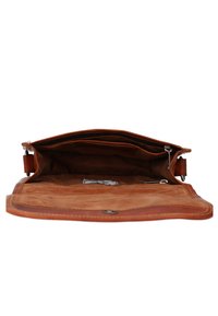 Brązowa skórzana torba z zamkiem błyskawicznym i przestronnym wnętrzem. Wnętrze ma gładką fakturę i małą etykietę z tkaniny.