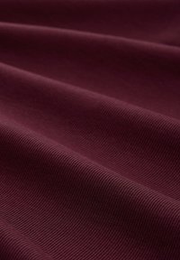 Bordeauxroter gerippter Stoff mit sichtbaren horizontalen Falten und weicher Textur.