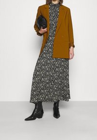 Hnědá dvouřadá blazer přes černé květinové maxi šaty. Černá psaníčko a černé kotníkové boty na podpatku. Hladká látka, dobře padnoucí střih.