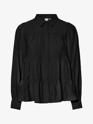 Blusa nera con bottoni, colletto, corpetto arricciato e peplum a strati. Realizzata in un tessuto morbido e leggermente testurizzato con maniche lunghe.