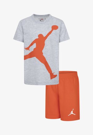 Siva pamučna majica s narančastom siluetom igrača, uparen s narančastim šortsem s bijelim logotipom. Mekana, ležerna sportsku odjeću.