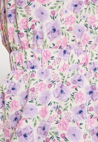 Vestido floral com um fundo creme claro, apresentando rosas roxas e cor-de-rosa e folhagem verde. Cintura franzida com pregas. Textura de tecido suave.