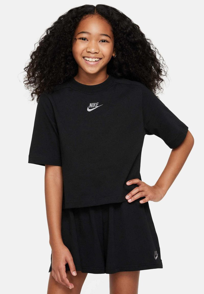 T-shirt cropped nera Nike con maniche corte, con logo bianco sul petto. Abbinata a pantaloni corti neri, in morbido cotone, vestibilità casual.