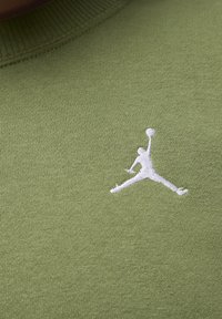 Felpa verde oliva realizzata in tessuto liscio, con un logo Jumpman ricamato in bianco sul petto. Collo rotondo con finiture a costine.