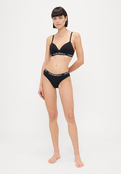 Soutien-gorge noir sans coutures avec bretelles réglables et décolleté plongeant, assorti à une culotte noire avec une taille ornée du logo.