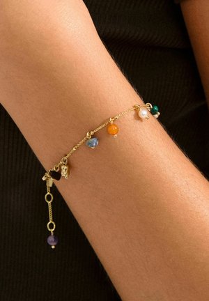 Gouden armband met een delicaate ketting, kleurrijke kralen in oranje, blauw, groen en paars, met kleine bedelaccenten en een decoratieve sluiting.