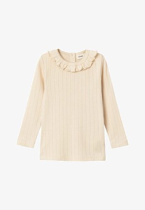 Pikendustega heledast beežist ribatootest valmistatud pikkade varrukatega pluus, millel on volangkaelus. Omab peent horisontaalset triibustust ja nupulausu taga.