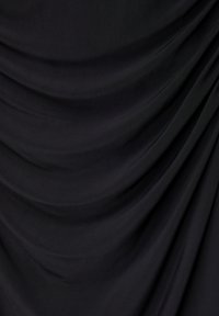 Tissu noir lisse avec des plis doux et naturels créant des courbes douces et fluides ainsi que des ombres sur toute la surface.