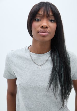 Sivá bavlnená tričko má okrúhly výstrih a krátke rukávy. Modelka nosí strieborný náhrdelník s krížovým príveskom. Dlhé, rovné vlasy majú modré melíry.