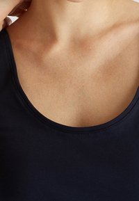 Top in stile canotta blu navy con scollatura arrotondata e spalline sottili, realizzato in un tessuto liscio ed elastico con un design aderente.