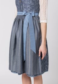 Blaues Kleid mit gemustertem Oberteil und gestreiftem Rock. Besitzt ein breites, weiches Band in der Taille. Der Stoff hat eine strukturierte Optik.