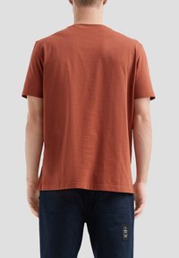 Roestkleurig katoenen T-shirt met een ronde hals en korte mouwen, met een casual pasvorm en subtiele textuur. Geen zichtbare patronen of accenten.