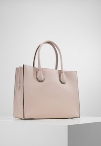 Beige läderväska med strukturerad yta, rektangulär form, dubbla handtag och svart kantlist längs kanterna. Enkla metalldetaljer.