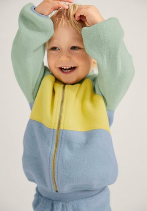 Fleece zip-up jack in groen, geel en blauw. Kenmerkt zich door een zachte textuur, een losse pasvorm en ribgebreide boorden. Voorzien van een rits aan de voorkant.