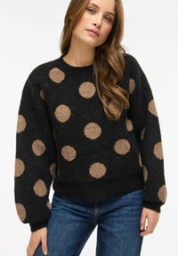 Must värviline kampsun suurte beežide täppidega, tekstuurse kangaga, soonikuga kaeluse ja mansettidega ning lõdva istuvusega. Sobitatud siniste teksadega.