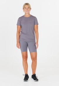 Kortärmad grå idrottströja tillsammans med matchande grå shorts. Bärs med svarta sportskor. Slät, fukttransporterande material.