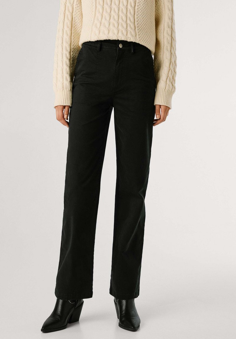 Zwarte wijde broek van gestructureerde stof, met een hoge taille, voorzakken en een knoopsluiting, gecombineerd met zwarte hakken.
