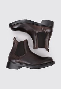 Bottes Chelsea en cuir marron avec des panneaux latéraux élastiques, une languette et une semelle en caoutchouc noir épaisse. Texture lisse avec un design élégant.