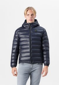 Navy blue puffer jacket with a zippered front, removable hood, and elastic cuffs. Made from glossy, lightweight material with quilted padding.