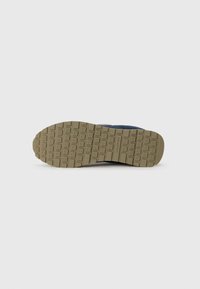 Shoe sole with a textured rubber surface, featuring square patterns. The color is khaki with a dark blue upper part visible along the edge.