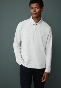 Light gray long-sleeve polo shirt with a collar and a single black button. Features raglan sleeves and a textured fabric.