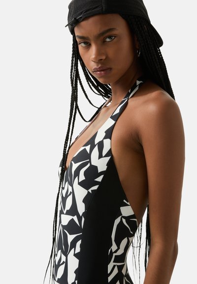 Maillot de bain une pièce avec un motif abstrait en noir et blanc, décolleté plongeant et découpes sur les côtés. Fabriqué dans un matériau lisse et extensible.