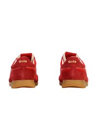 Zapatillas de ante rojo con suela acolchada, detalles en blanco contrastante y un logotipo dorado de "Gola" cosido en la parte trasera.