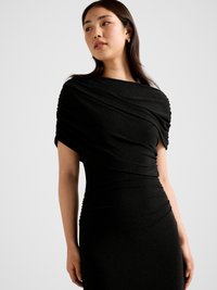 Must kleit, mille ülaosas on voltidega draperii ja keha järgnev siluett. Kangal on õrn sära ning õlgadel ja vööl on kogutud detailid.