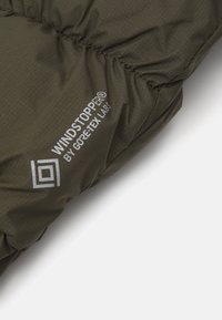 Roheline tuulekindel kangas, millel on tikandite tekstuur, koos valgega trükitud "WINDSTOPPER® by GORE-TEX LABS" logoga.