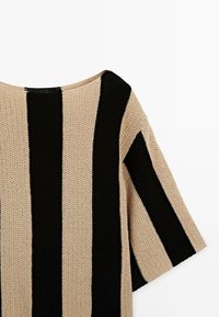 Haut en tricot beige et noir à larges rayures verticales et manches courtes, mettant en valeur un tissu texturé et un col rond.