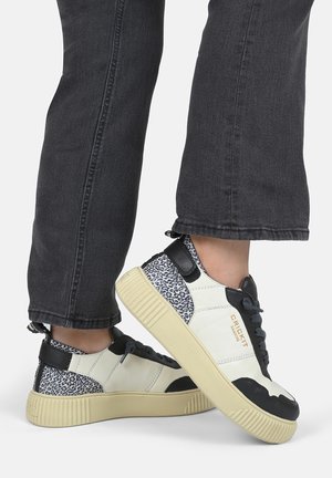 Witte en zwarte leren sneakers met een gekarteld dierenprint op de hak, ronde neus en dikke rubberen zool in een lichte tint.