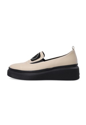 Beige leather slip-on shoe with a black textured platform and decorative black accent on the upper. Features a rounded toe and back loop.