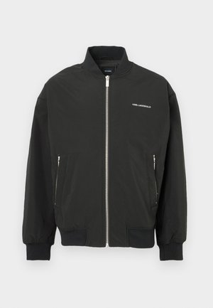 Veste bomber noire avec fermeture éclair à l'avant, deux poches latérales, poignets et ourlet côtelés, avec le logo blanc "KARL LAGERFELD" sur la poitrine.