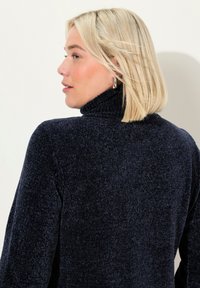 Maglione a collo alto di colore blu navy, realizzato in un morbido materiale a maglia con una silhouette aderente e maniche lunghe.