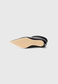 Scarpa nera a punta con tomaia in pelle liscia e un accento in pelle verniciata strutturata. Suola in gomma beige con motivo rigato per una migliore trazione.