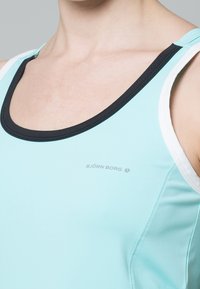 Jasnoniebieski sportowy top na ramiączkach z czarnym dekoltem i białymi akcentami na ramiączkach, z małym logo "BJÖRN BORG" pośrodku.