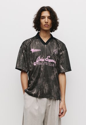 Black sports jersey with a marbled pattern, pink text "Asha Square Sports Club," and a contrasting black V-neck collar. Short sleeves.