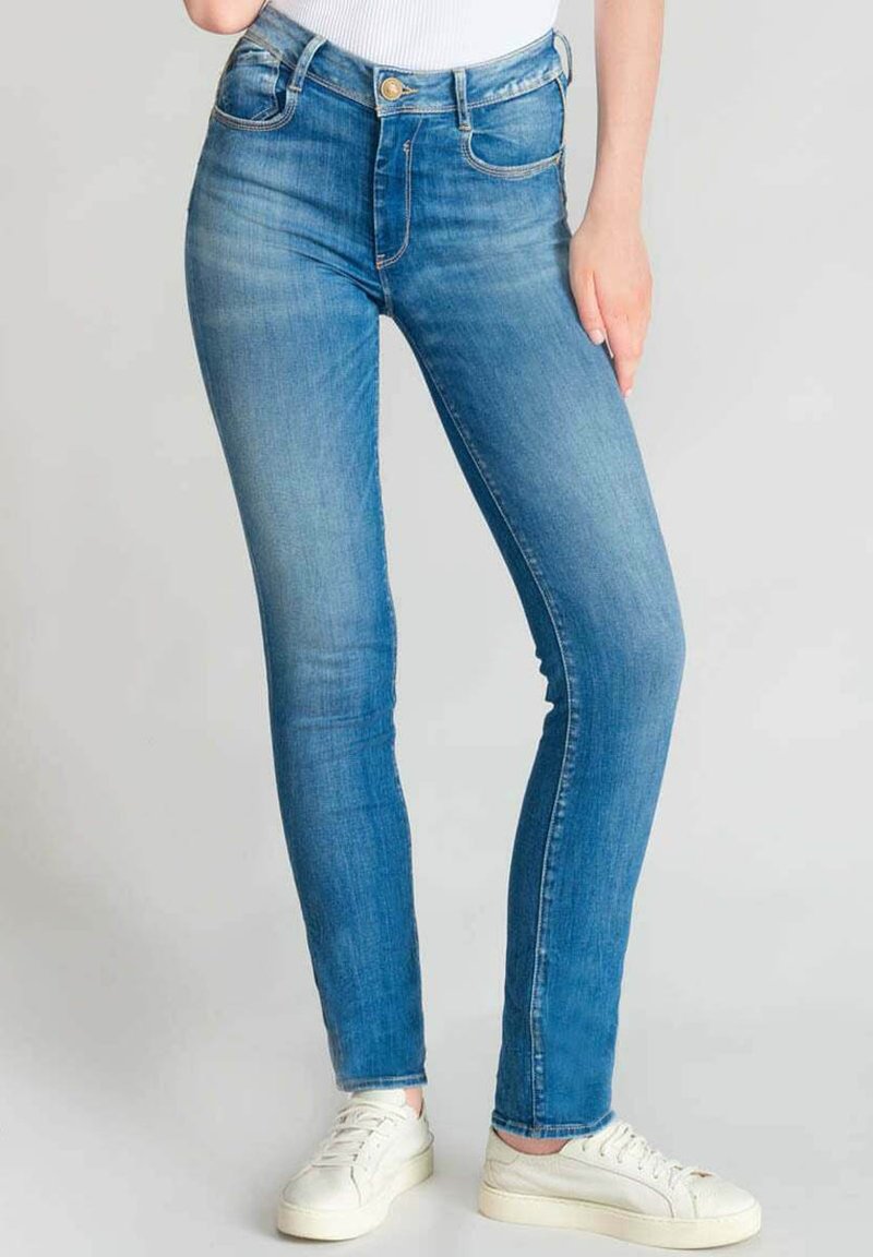 Jean skinny bleu en denim avec une taille haute, dotés de deux poches avant et d'une fermeture à un bouton. Portés avec des baskets blanches.