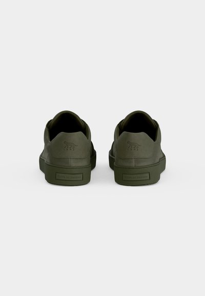 Ζευγάρι σκούρα πράσινα sneakers χαμηλού τύπου από πίσω, με λογότυπο "Tiger of Sweden" και ανάγλυφο σχέδιο τίγρης στις πίσω λουρίδες.
