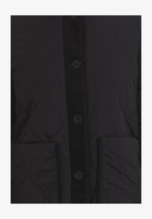 Veste matelassée noire avec un plastron en velours côtelé, cinq boutons et deux poches latérales. Texture lisse avec un motif ondulé subtil sur le tissu.