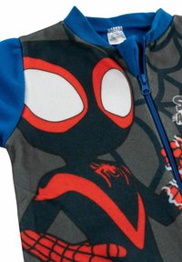 Tuta in pile con colletto blu, chiusura con zip e grafica di Spider-Man in rosso e nero su uno sfondo grigio con motivi di ragnatela.
