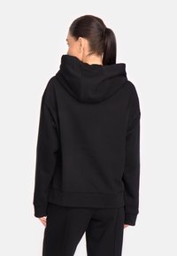 Must kleid, mis on valmistatud pehmest kangast, omab lahtist lõiget, soonikuid mansete juures ning küülikutaskut. Tagantvaade on näidatud.