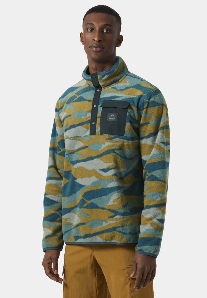Pullover de forro polar multicolor en un patrón de camuflaje azul, verde y amarillo. Presenta un cuello alto, una tapeta de cinco botones y un bolsillo en el pecho.
