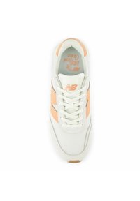Sneaker bianco con accenti pesca, materiale in rete e sintetico, punta arrotondata, design con lacci, suola testurizzata e branding sulla linguetta e sul lato.