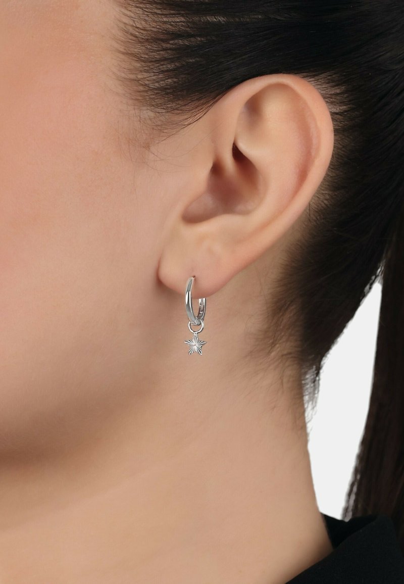 Orecchino a cerchio in argento con ciondolo a forma di stella. La stella presenta raggi testurizzati che si irradiano da un punto centrale, creando un design distintivo.