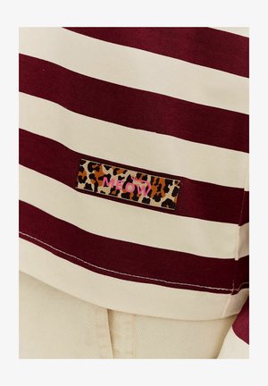 Pruhované bavlněné tričko v barvách mahagonové a krémové, s nášivkou s leopardím vzorem a nápisem "MEOW" v růžovém textu. Standardní design s kulatým výstřihem.