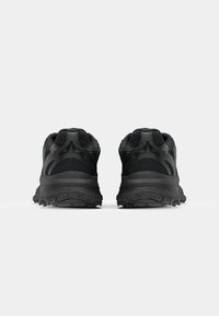Black athletic shoes with a textured surface, featuring a mesh upper, reinforced heel, and rubber outsole with traction lugs.